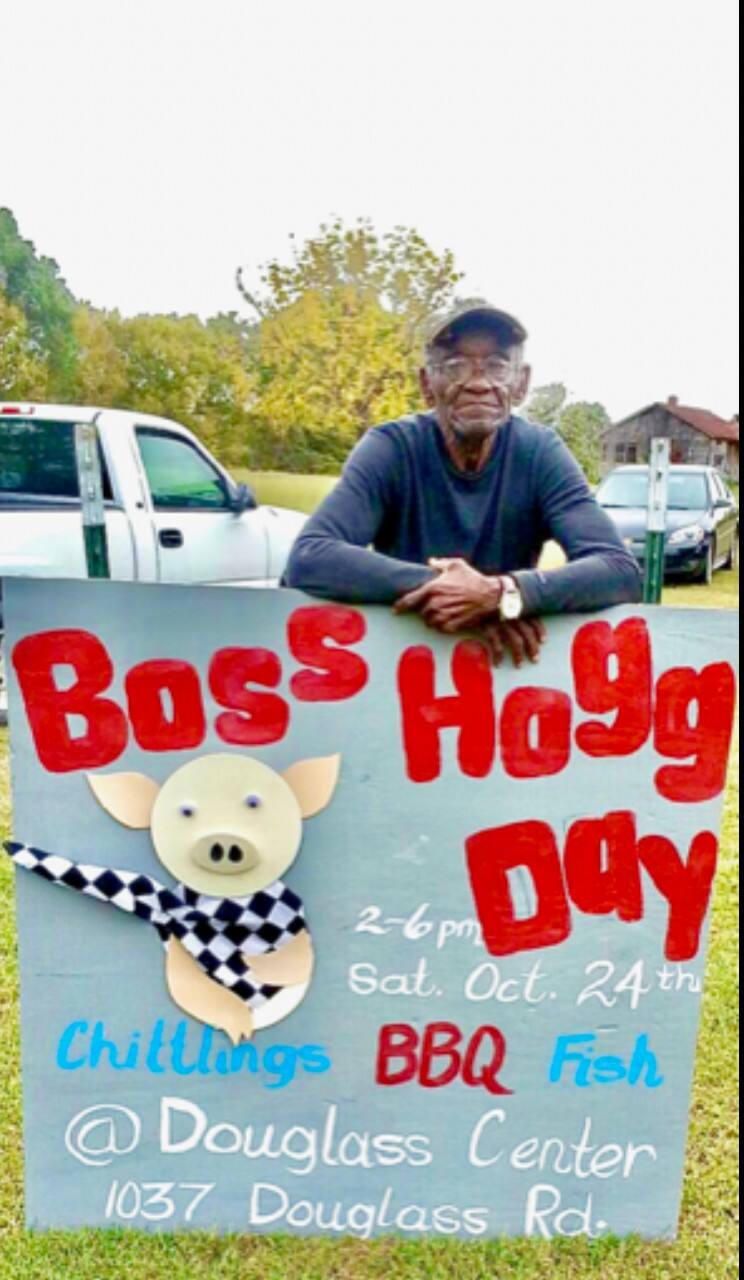 A community member holds up a sign for a barbeque.