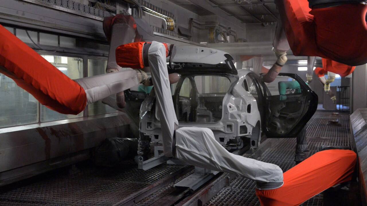 The assembly line automatically sprays a base coat on the vehicle frame