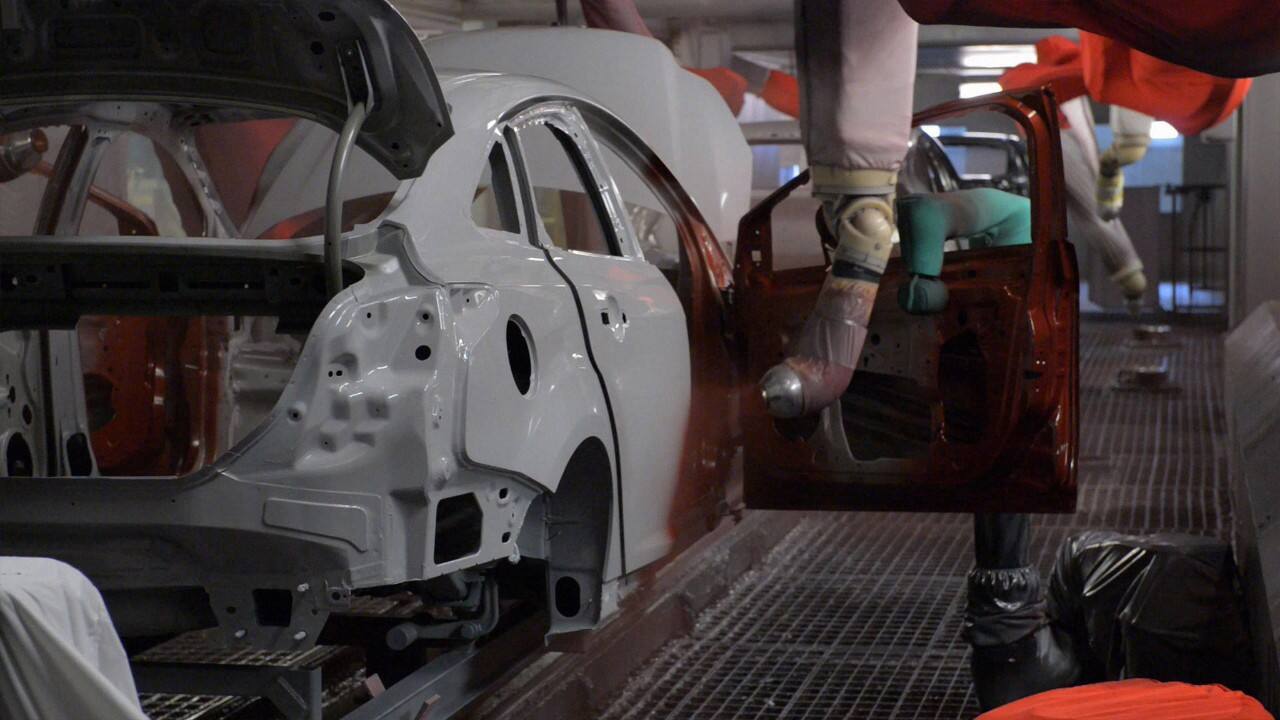 A vehicle frame moves along the paint assembly line
