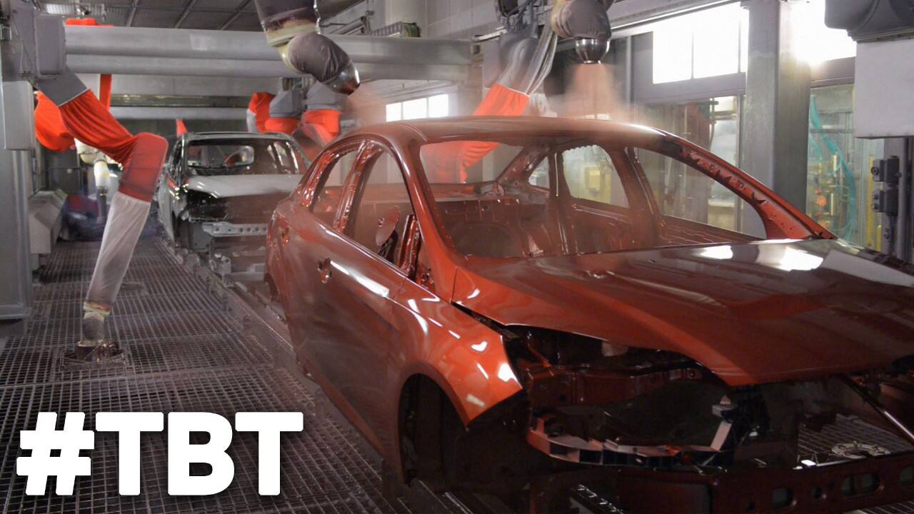 Automatic spray painters coat a vehicle frame with red paint
