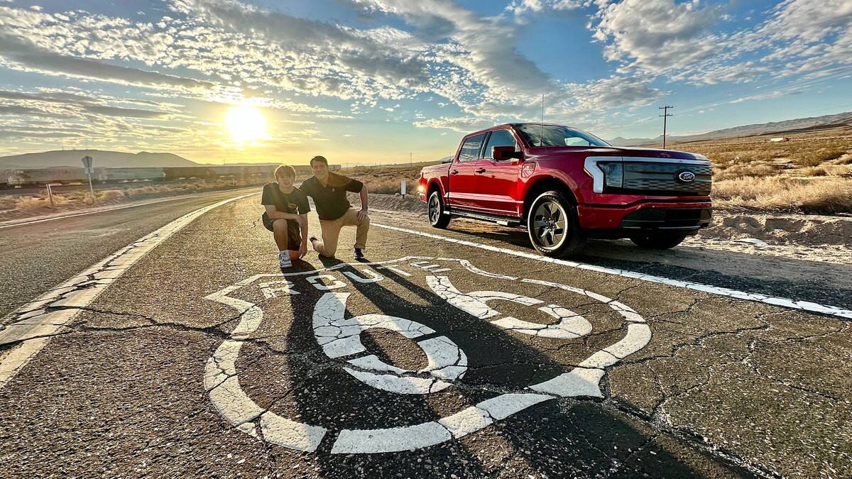 Jim Farley and his son on the Route 66 road with a red F-150 in the background