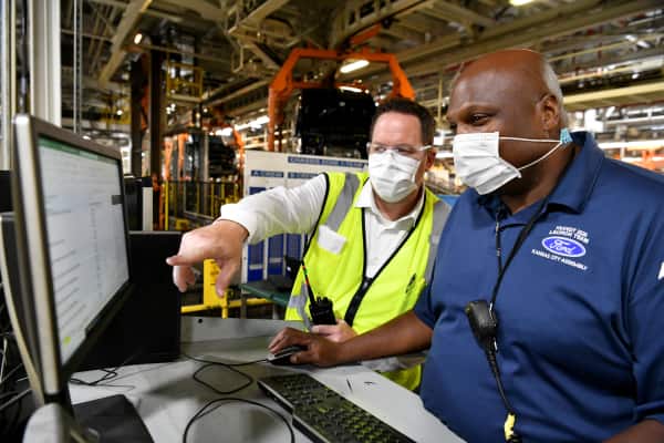 Ford employees stand at computer station in Ford facility